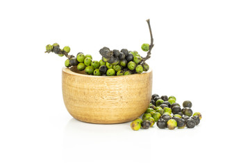 Unripe fresh black pepper grains in a wooden bowl isolated on white background.