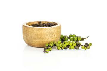 Unripe fresh black pepper grains with a wooden bowl isolated on white background.