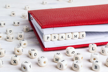 Word Psalms written in wooden blocks in red notebook on white wooden table. - obrazy, fototapety, plakaty