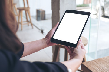 Mockup image of a woman holding black tablet pc with blank white desktop screen in cafe