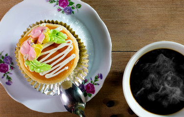 Cup cake with black coffee on wooden table