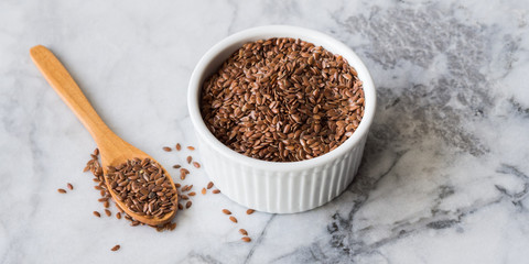 Flax seeds in white ramekin on marble board