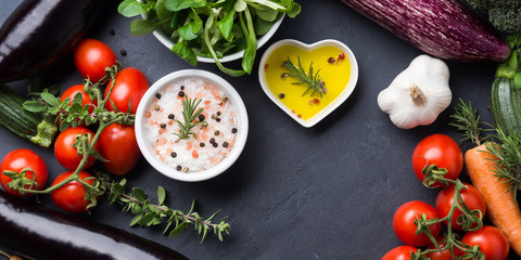 Mix of raw vegetables with salt, spices on dark background. Clean healthy eating concept