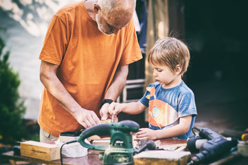 Grandfather and his grandson having fun in the outdoor workshop