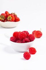 Summer fruits concept strawberry and rasberry in ceramic cup on white background with copy space