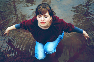 Mujer joven posando en equilibrio en un lago con ropa de invierno 