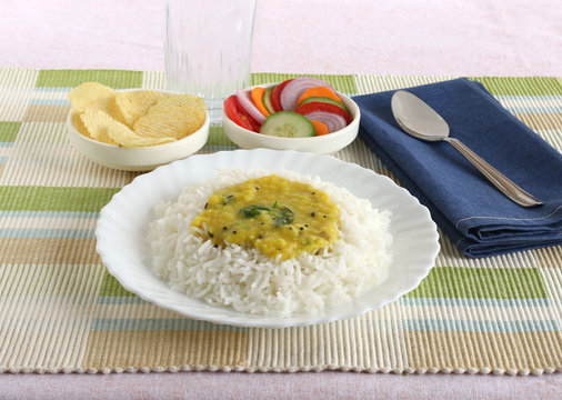 Dal and rice, healthy, traditional and popular Indian vegetarian and delicious lunch, with potato chips and salad as side dishes.