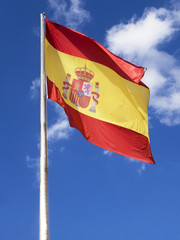 Flag of Spain, called La Rojigualda, waving on a blue sky.