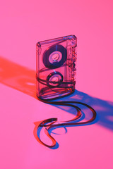 close up view of retro audio cassette and tape on pink backdrop
