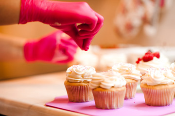 Woman decorating creamy cupcakes with fruits closeup. Cooking at home.