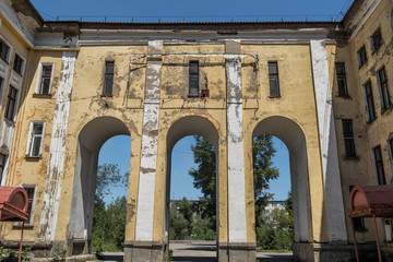 Fototapeta na wymiar Old abandoned hospital. Medical complex. Old architecture. Architectural heritage. Main entrance. Grunge architectural background. Blue sky