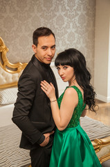 elegant guy and girl in luxury suites. Brown-haired woman in an emerald expensive dress and a guy in a black tuxedo. The life of rich people.