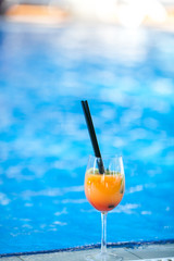 orange cocktail on swimming pool background.Summer vacation concept. Refreshing beverage.vertical shot. copy space