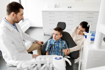 Obraz premium medicine, dentistry and healthcare concept - mother and son visiting dentist at dental clinic