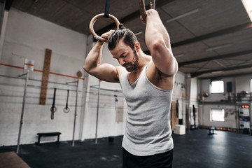 Fit young man taking looking tired after exercising on rings