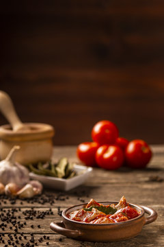 Meat and tomato meal with fresh vegetables and ingredients on dark background