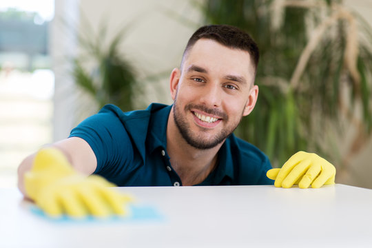 Household, Cleaning And People Concept - Smiling Man Wiping Table With Cloth At Home