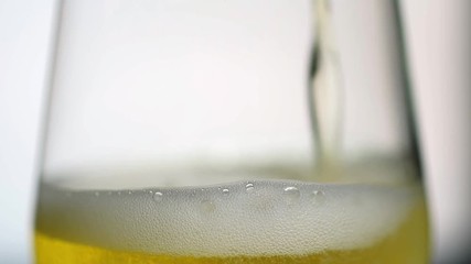 Slow motion shot of pouring a glass of beer on a white background