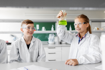 education, science and children concept - kids with test tubes studying chemistry at school...