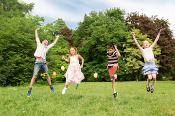 summer holidays, childhood and frinedship concept - happy kids having fun and jumping in park
