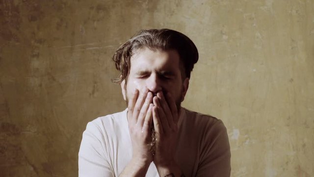 man bends over and rejuvenates himself with a splash of cool, fresh water on his face.
