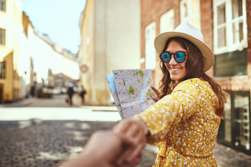 Smiling woman holding a map leading someone through city streets