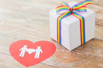 homosexual and lgbt concept - close up of gift box with gay pride awareness ribbon and male couple...