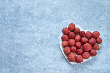 Fresh strawberry in heart shape on concrete background. Top view, copy space. Minimalism. Summer concept
