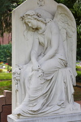 Cemetery sculpture of mourning angel sitting with cloth