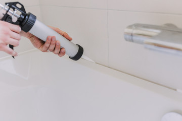 hands of man putting a silicon with a silicon tube in bathroom - obrazy, fototapety, plakaty