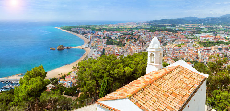 Coast, Chapel of John Baptist, rock Sa Palomera and architecture of Spanish beach resort Blanes in summertime. Sunny panorama from height of mountain of castle San Juan. Costa Brava, Catalonia, Spain