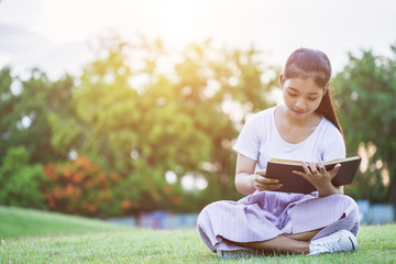 Pretty asian girl or students reading a book in the public park