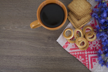 cup of coffee, bagels and biscuits, flowers of a cornflower on a wooden background