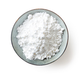 Bowl of powder sugar on white background, from above