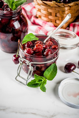 Homemade preserved cherry and mint jam, with fresh cherries on white marble background copy space