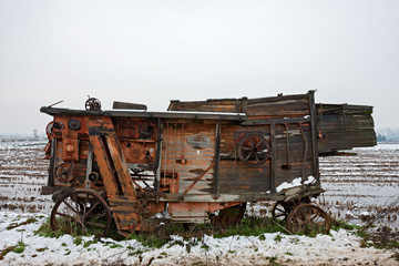 View of a rice field in winter with snow and an old agricultural machine.