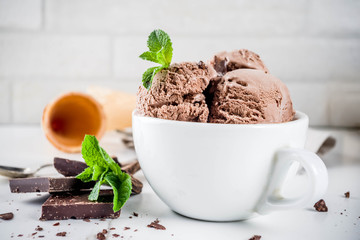 Homemade chocolate ice cream served with fresh mint, dark chocolate and waffle ice cream cones, white marble background copy space