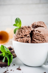 Homemade chocolate ice cream served with fresh mint, dark chocolate and waffle ice cream cones, white marble background copy space