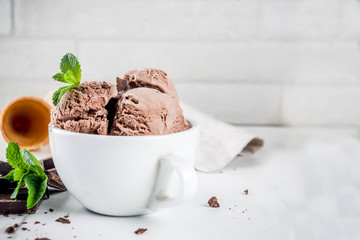 Homemade chocolate ice cream served with fresh mint, dark chocolate and waffle ice cream cones, white marble background copy space