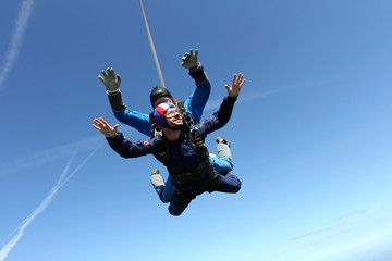 Skydiving. Two men are flying in the blue sky.
