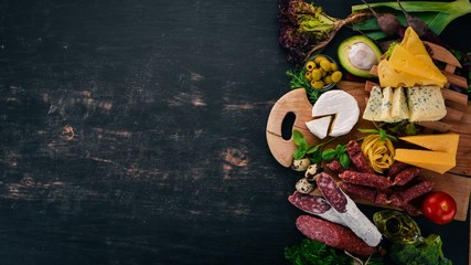 Sausage, cheese and vegetables. Assortment of food. On a wooden background. Top view. Copy space.