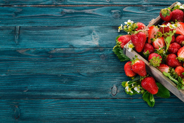 Fresh strawberries in a wooden box. On a wooden background. Top view. Copy space.