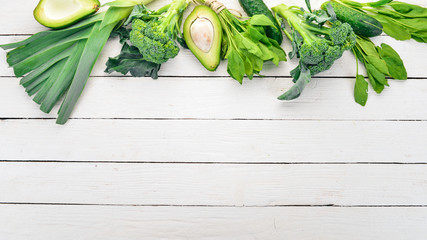 Green vegetables and fruits. On a white wooden background. Healthy food. Top view. Copy space.