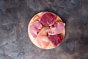 Mockup of raw chicken, beef and pork on cutting board set on wooden round board. Lean proteins.