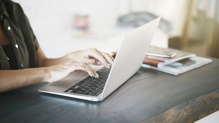 Close up of white woman hands on black keyboard of a laptop at home