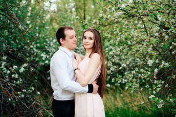 Naklejka premium a young couple in love in the spring flowering Park