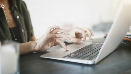 Close up of white woman hands on black keyboard of a laptop at home