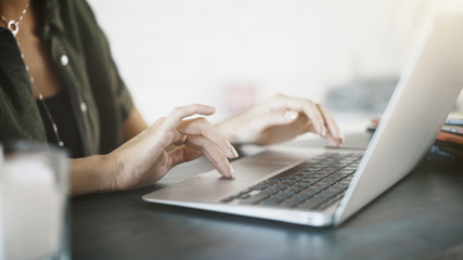 Close up of white woman hands on black keyboard of a laptop at home