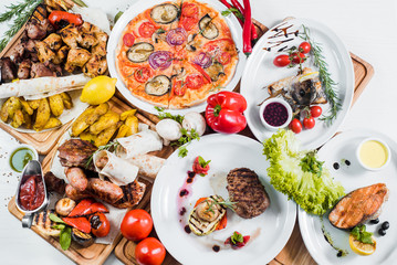 Big set of different dishes with meat, vegetables, pizza and spices flatlay on white background