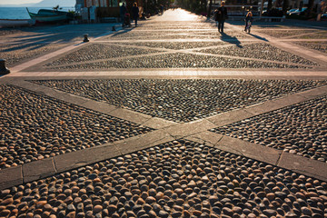 Some people stroll along the promenade in the light of the sunset.